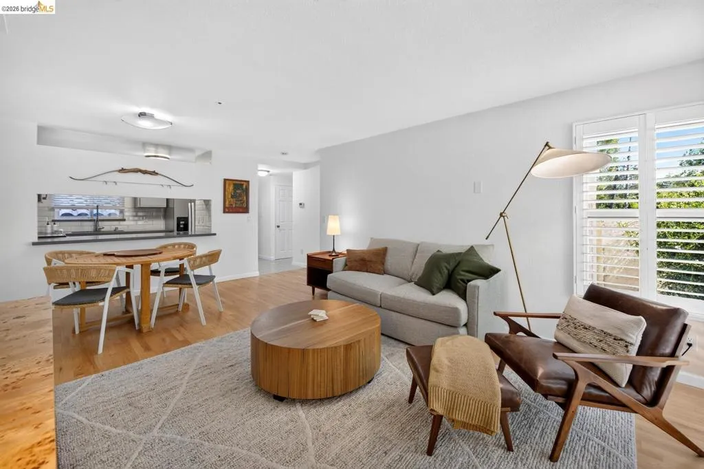 Light wood-finish flooring throughout, white walls, and a recessed pass-through window with a dark countertop Light wood-finish flooring throughout, white walls, and a recessed pass-through window with a dark countertop