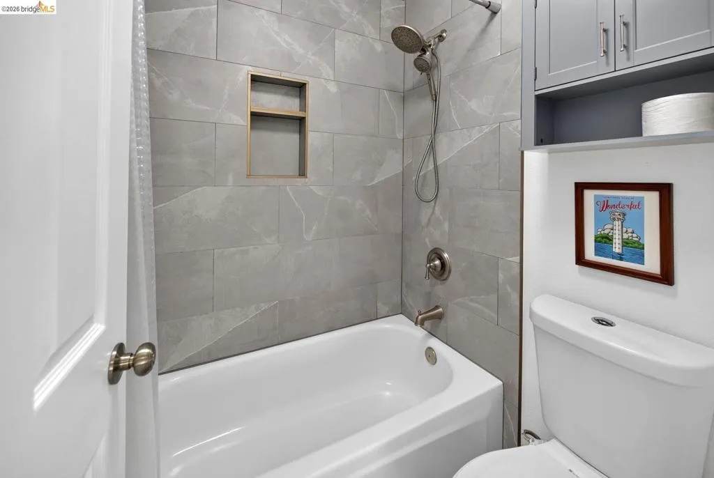 Tub/shower combination with large format tiled surround, built-in shower niche, and brushed nickel fixtures Tub/shower combination with large format tiled surround, built-in shower niche, and brushed nickel fixtures