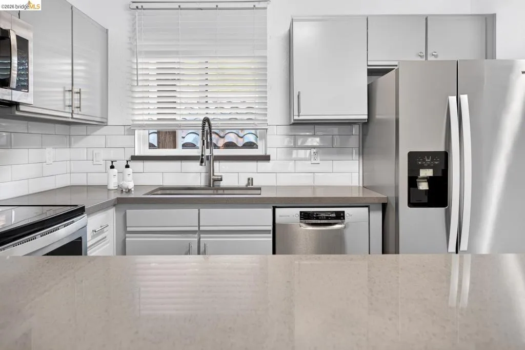 Stainless steel appliances, white subway tile backsplash, light-toned countertops, and light gray cabinetry Stainless steel appliances, white subway tile backsplash, light-toned countertops, and light gray cabinetry