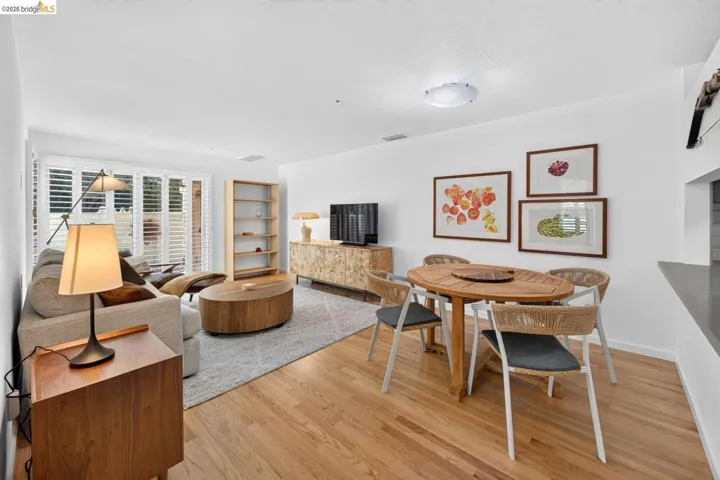 Open-concept living area with wood-finish flooring, plantation shutters, and a dining area with a built-in countertop