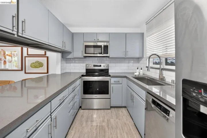 U-shaped kitchen featuring light gray cabinetry, stainless steel appliances, and a subway tile backsplash
