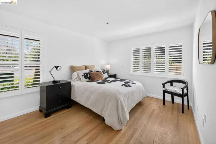 Light wood-finish flooring, white walls, and multiple windows with white plantation shutters
