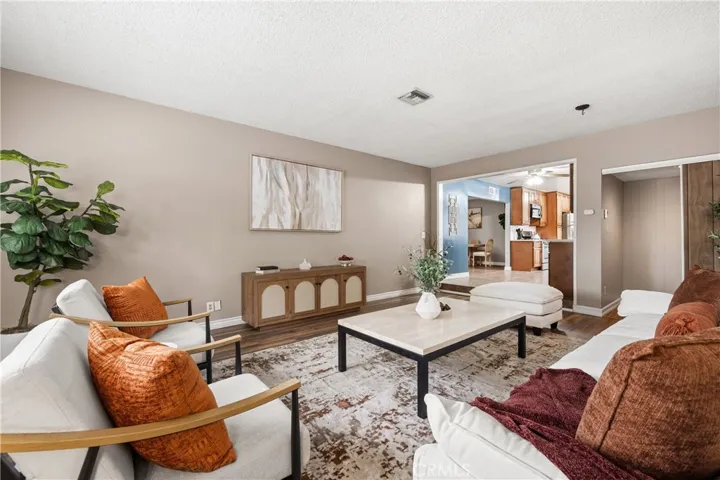 Spacious family room with warm wood-style flooring and an open flow into the kitchen and dining areas—ideal for everyday living and entertaining.