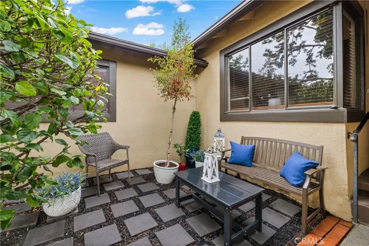 Inviting front patio seating area creates a charming outdoor space to relax and enjoy the mature landscaping surrounding this North Hills home.