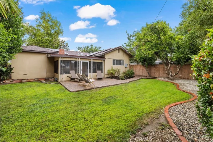 Another view of the spacious backyard highlights the lawn, mature landscaping and brick-paver patio surrounding the home.