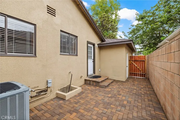 Brick-paver side yard provides convenient exterior access and additional functional outdoor space.