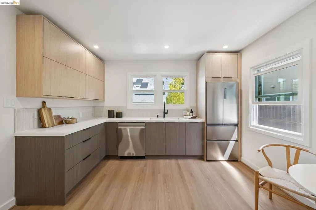 Kitchen featuring wood-finish flooring, white countertops, stainless steel appliances, and two-tone cabinetry