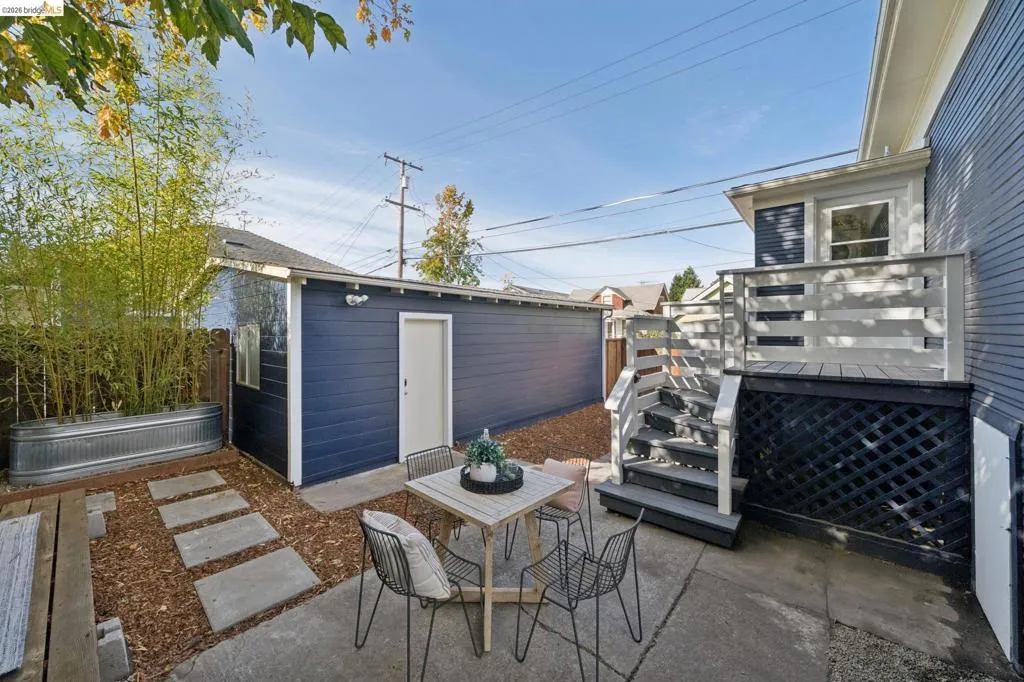 Concrete patio with a wooden deck featuring a slatted railing, exterior stairs, and a lattice foundation skirt