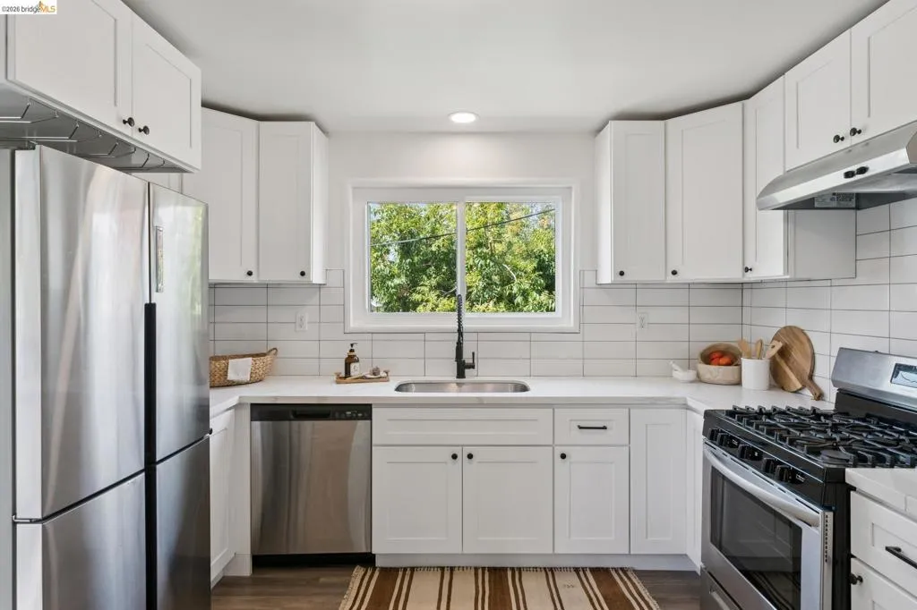 Modern kitchen with white shaker cabinetry, stainless steel appliances, white subway tile backsplash, and dark wood-finish flooring