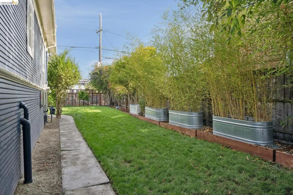 Expansive grass lawn with a concrete pathway and wood-sided exterior