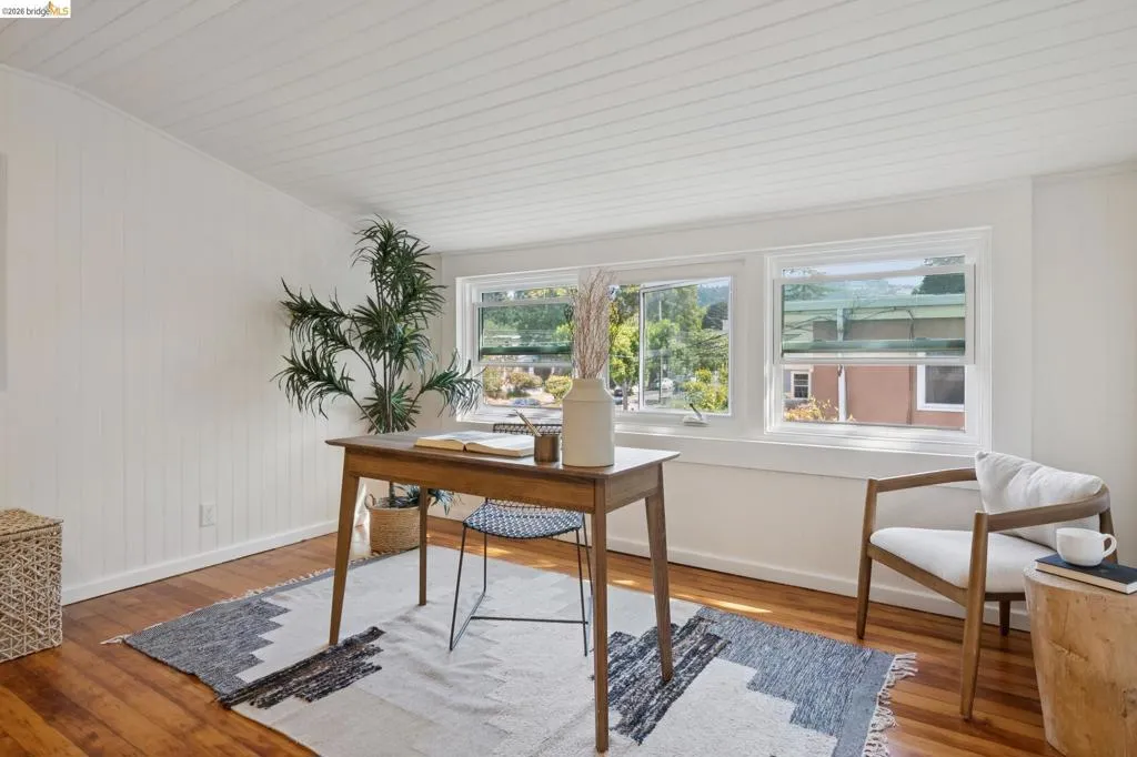 Wood-finish flooring, white paneled walls, white paneled ceiling, and multiple windows