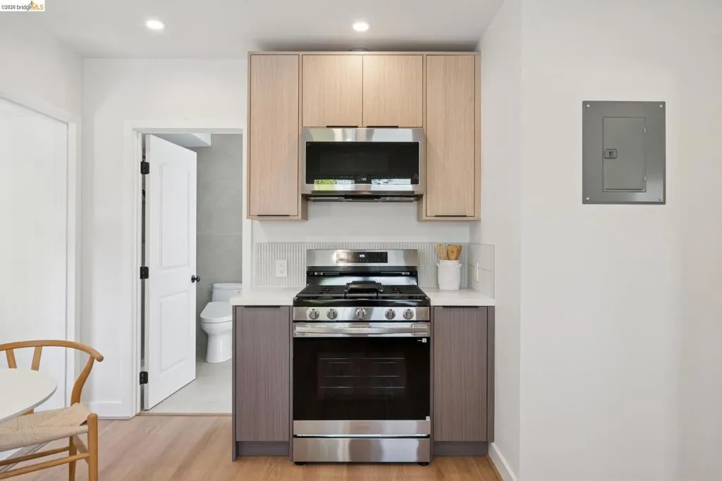 Stainless steel range with an overhead microwave, light-toned upper cabinetry, and contrasting lower cabinetry