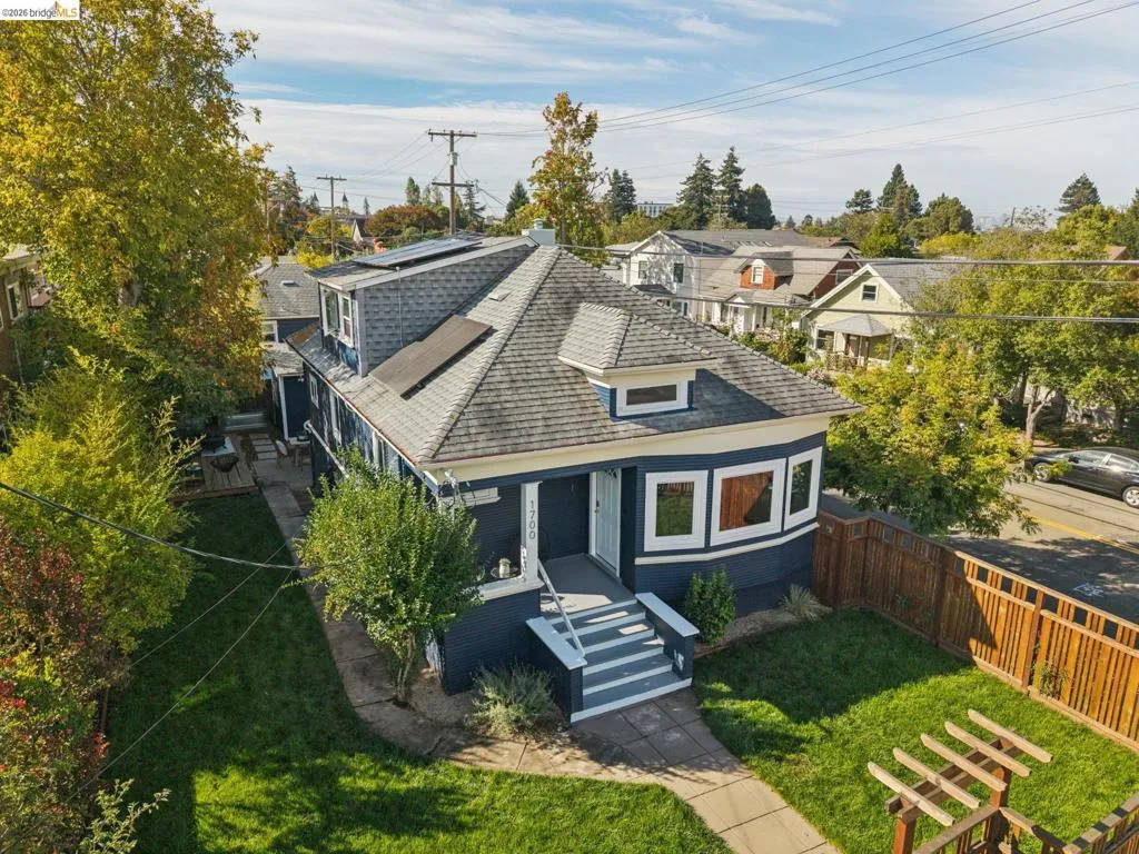 Two-story residence featuring a shingled roof, solar panels, and a landscaped front yard with a concrete pathway