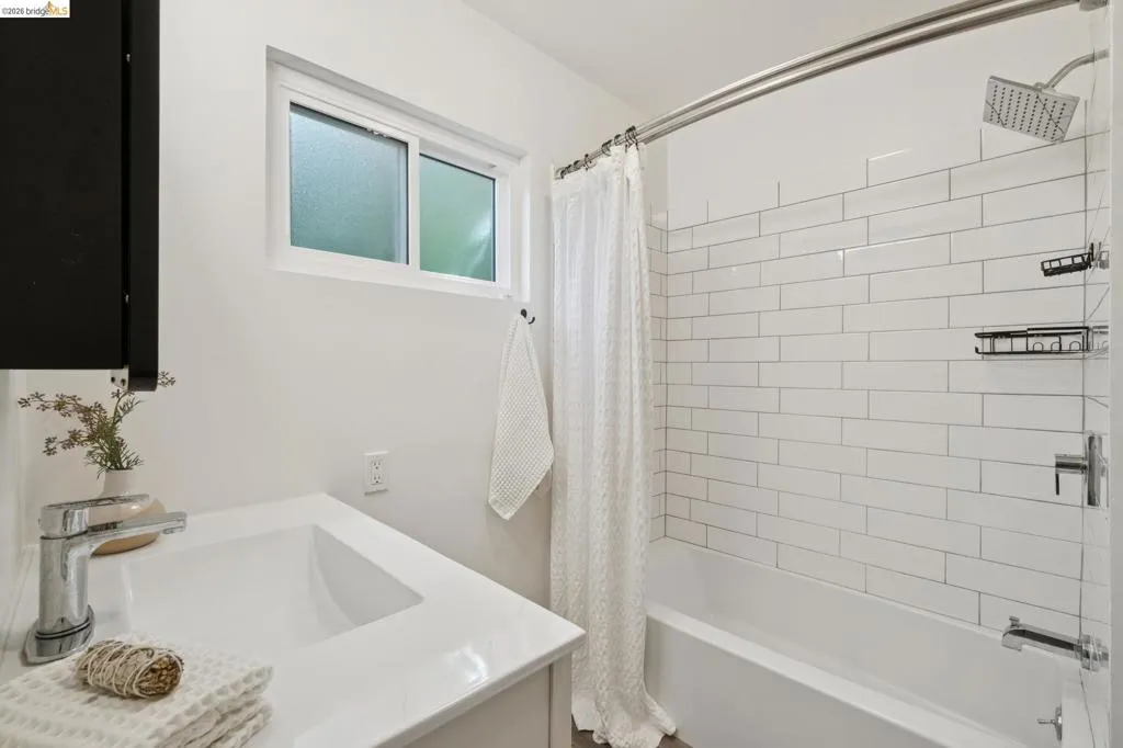 White subway tile shower surround with a rain shower head, chrome fixtures, and built-in shelving