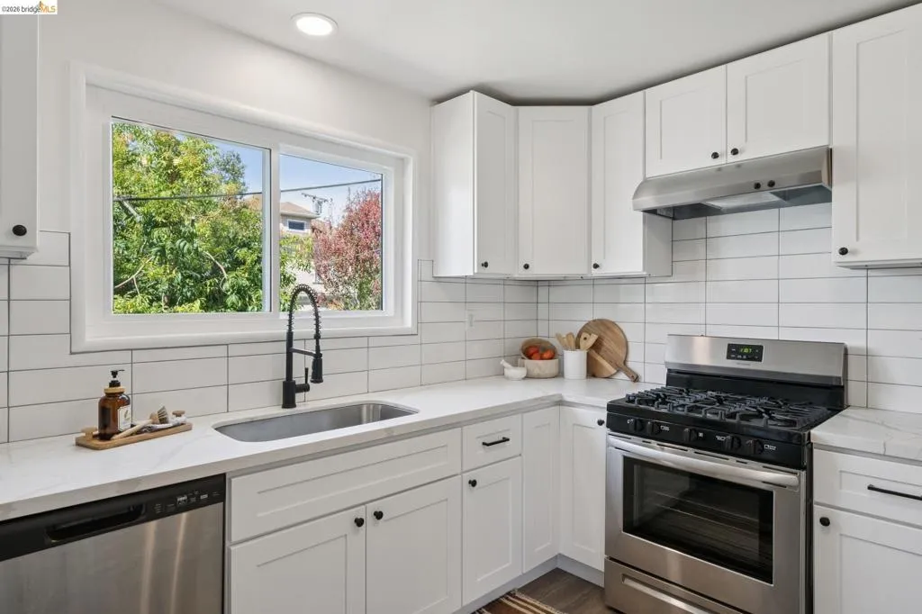 Kitchen featuring white shaker cabinetry, white subway tile backsplash, stainless steel appliances, and a stainless steel sink with a matte black faucet