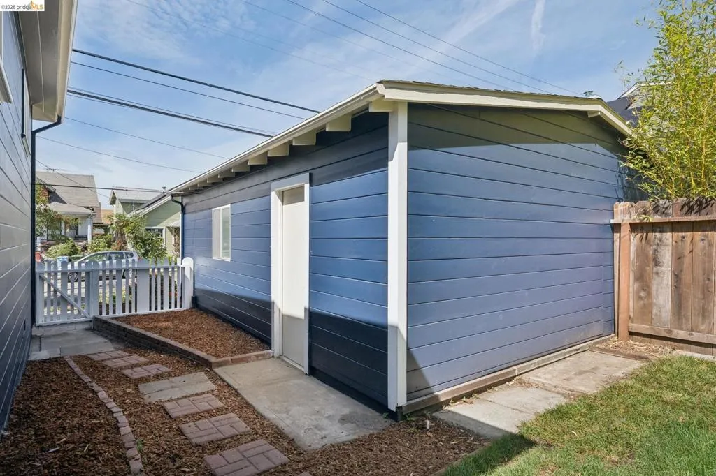 Detached structure featuring blue horizontal siding, white trim, and a white entry door
