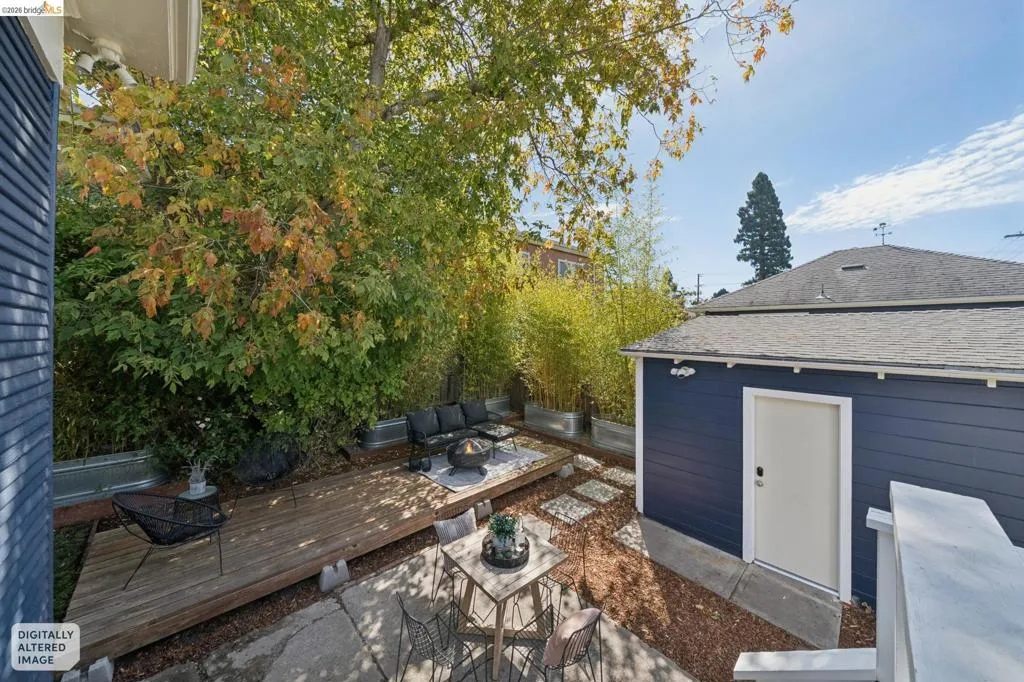 Expansive backyard featuring a wood deck, concrete paver patio, wood chip ground cover, and mature trees