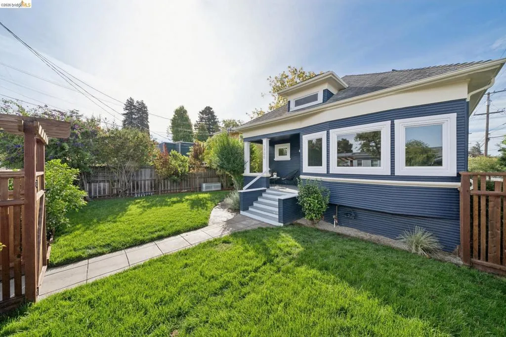 Exterior featuring blue siding, white trim, a covered porch, multiple windows, and a landscaped yard with a concrete pathway