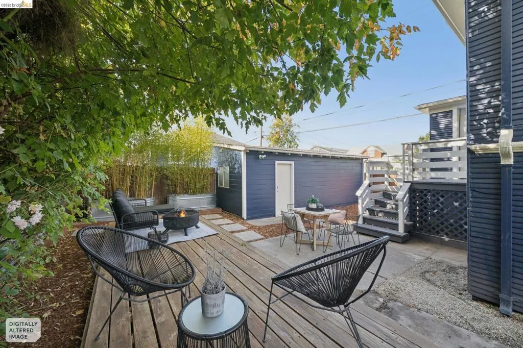 Expansive backyard featuring a wood deck, concrete patio, garden beds, and built-in steps with railings