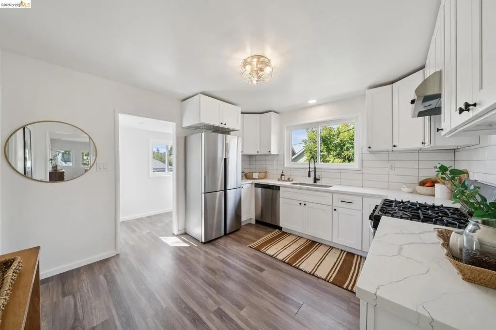Modern kitchen featuring white shaker cabinetry, stainless steel appliances, white subway tile backsplash, and quartz countertops with a gas range
