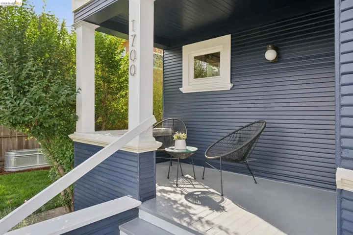 Painted wood siding with contrasting trim, covered front porch, white painted columns, exterior wall-mounted light fixture, and address numbers