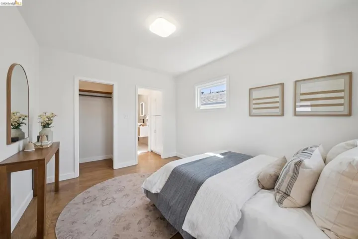 Hardwood-style flooring throughout, white painted walls, and a built-in closet with hanging rod