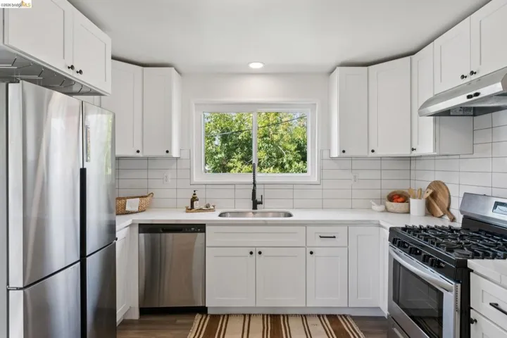 Modern kitchen with white shaker cabinetry, stainless steel appliances, white subway tile backsplash, and dark wood-finish flooring