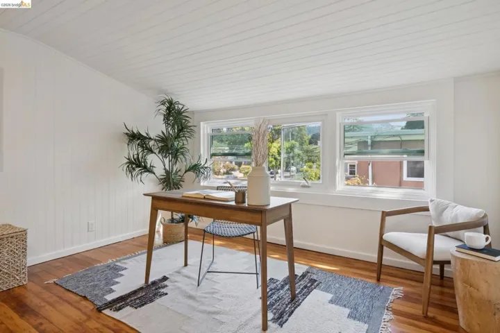 Wood-finish flooring, white paneled walls, white paneled ceiling, and multiple windows