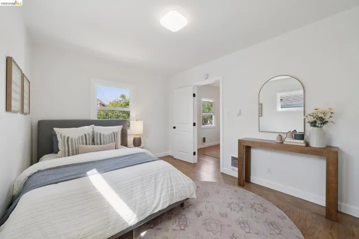 Wood-finish flooring, white walls, white trim windows, and a flush-mount ceiling light