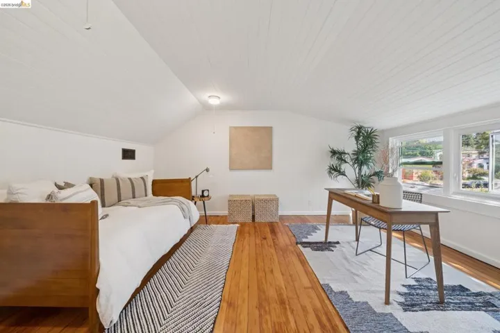 Vaulted ceiling with horizontal wood paneling, wood-finish flooring, and multi-pane windows