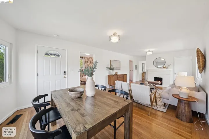 Hardwood flooring throughout, white interior walls, ocean air paneled door with arched glass insert, ceiling-mounted light fixtures, and a navajo fireplace mantel