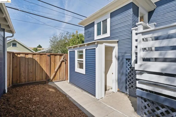 Backyard space featuring a wood fence, concrete pathway, and a detached structure with siding