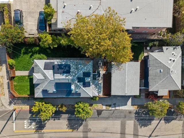 3 buildings on one lot.  Multiple solar panels installed on the roof, mature trees, and a grassy lawn area