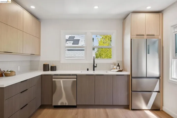 Kitchen featuring wood-finish cabinetry, white countertops, a mosaic tile backsplash, stainless steel appliances, and wood-finish flooring