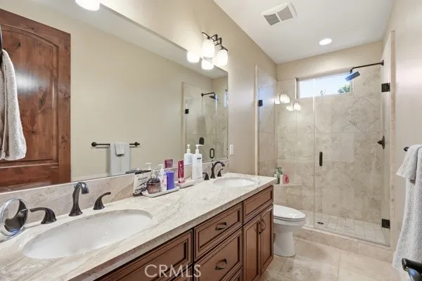 Spacious ground-level bathroom featuring dual vanities and a beautifully tiled walk-in shower.