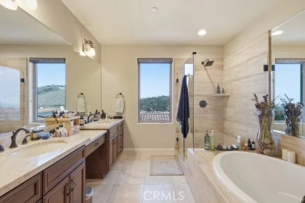 Luxurious primary bathroom with dual vanities, oval soaking tub, walking shower and private window framing beautiful scenic views.