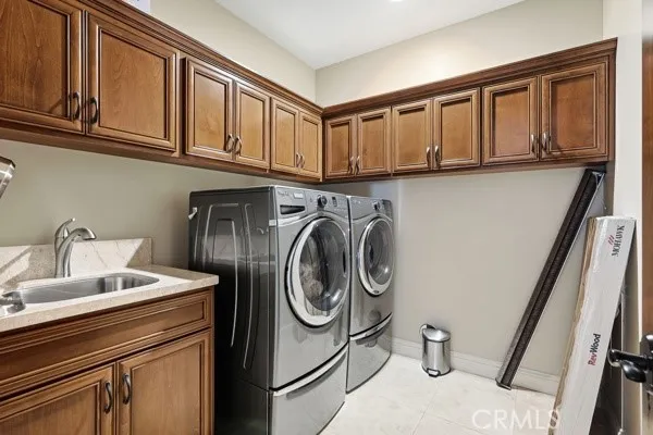 Laundry room with a utility sink and ample built-in cabinetry for storage.