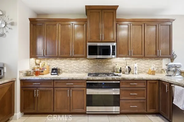 Well-appointed kitchen featuring rich wood cabinetry , granite countertops, and stainless-steel appliances.