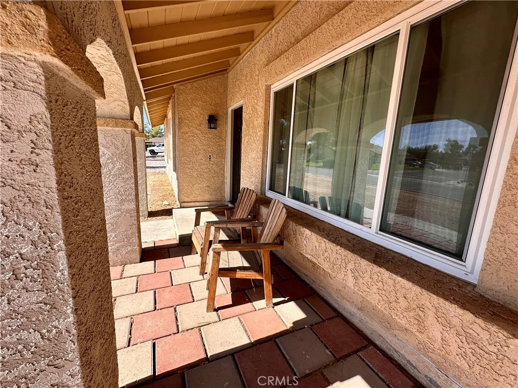A shaded entry porch with brick-style paver flooring, stucco columns, and space for outdoor seating creates a welcoming approach to the home. A shaded entry porch with brick-style paver flooring, stucco columns, and space for outdoor seating creates a welcoming approach to the home.