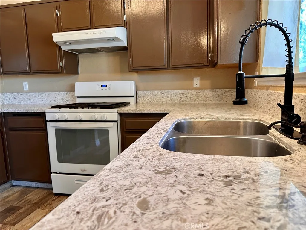 A closer look highlights the Quartz countertops, double-basin stainless steel sink, high-arc faucet, gas range, and ample cabinet storage. A closer look highlights the Quartz countertops, double-basin stainless steel sink, high-arc faucet, gas range, and ample cabinet storage.