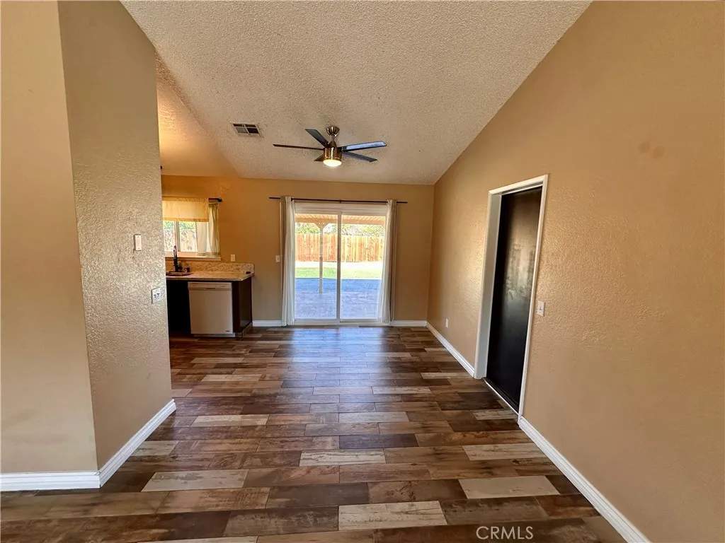 A spacious living area features wood-look flooring, a ceiling fan, fireplace, and sliding glass doors that provide easy access to the outdoor area. A spacious living area features wood-look flooring, a ceiling fan, fireplace, and sliding glass doors that provide easy access to the outdoor area.