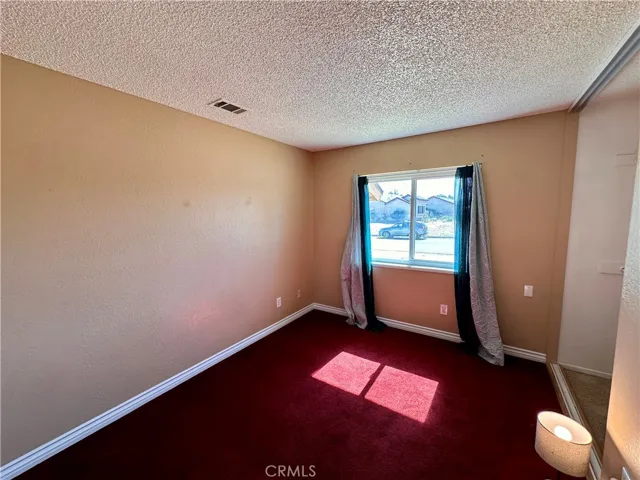 A bright bedroom offers a front-facing window, ample wall space, and rich carpeting for a warm, comfortable setting.