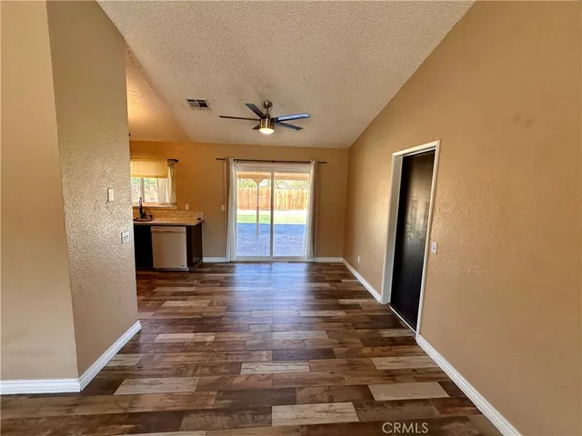 A spacious living area features wood-look flooring, a ceiling fan, fireplace, and sliding glass doors that provide easy access to the outdoor area.