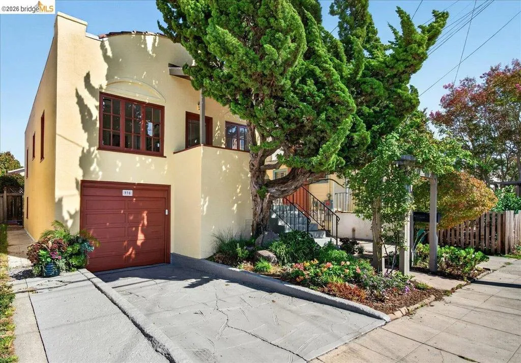 Stucco exterior with a terracotta garage door, integrated garage, concrete driveway, and established landscaping Stucco exterior with a terracotta garage door, integrated garage, concrete driveway, and established landscaping