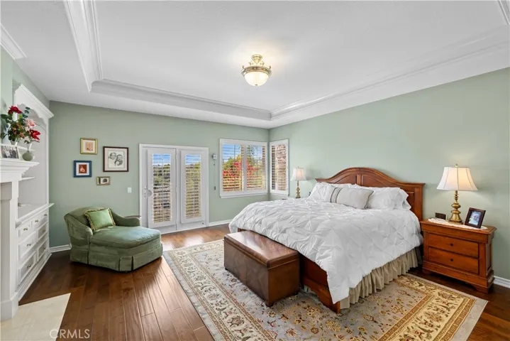Stunning Primary Suite with Exquisite Crown Molding, Plantation Shutters, Custom Built-In's and Elegant Fireplace.