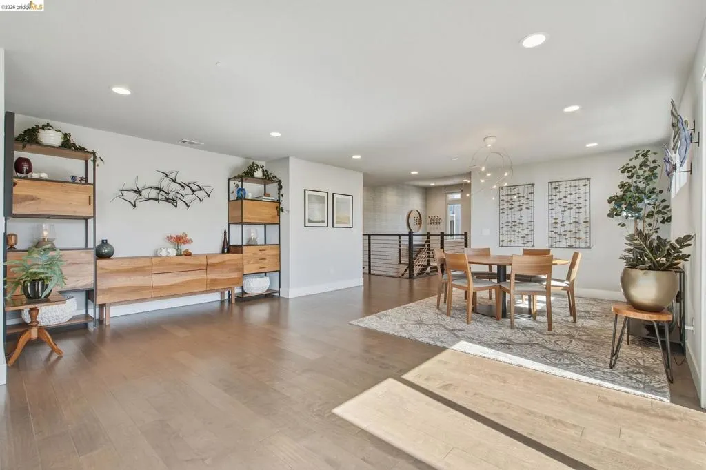 Expansive living area with wood-finish flooring, recessed lighting, and a modern chandelier
