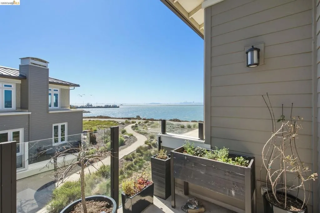 Outdoor balcony with glass panel railing and a water backdrop
