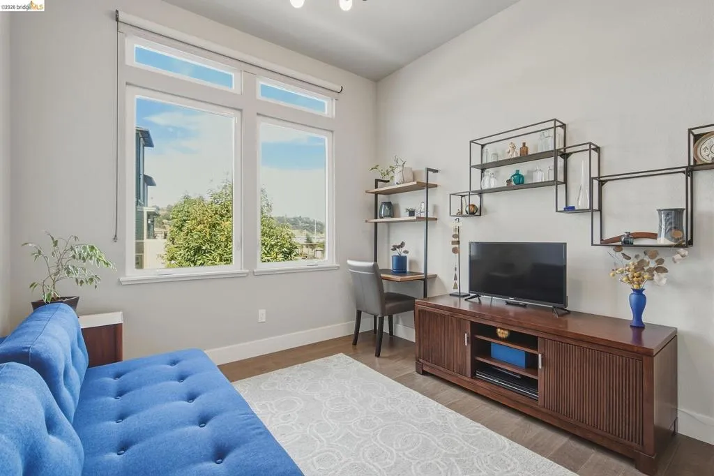 Expansive window system with transom windows, wood-finish flooring, built-in shelving, and a media console