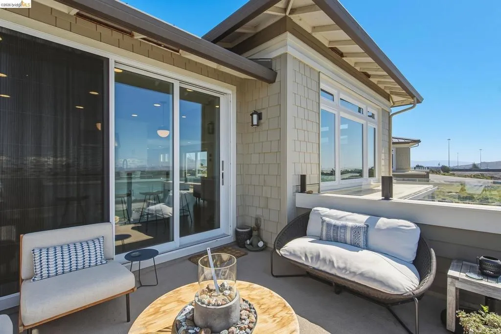 Spacious patio featuring a glass railing, large sliding glass doors, and shingle siding