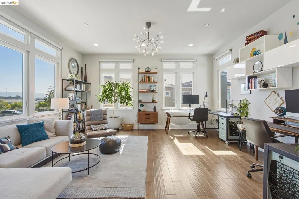 Expansive living area with large windows, wood-finish flooring, recessed lighting, and built-in shelving